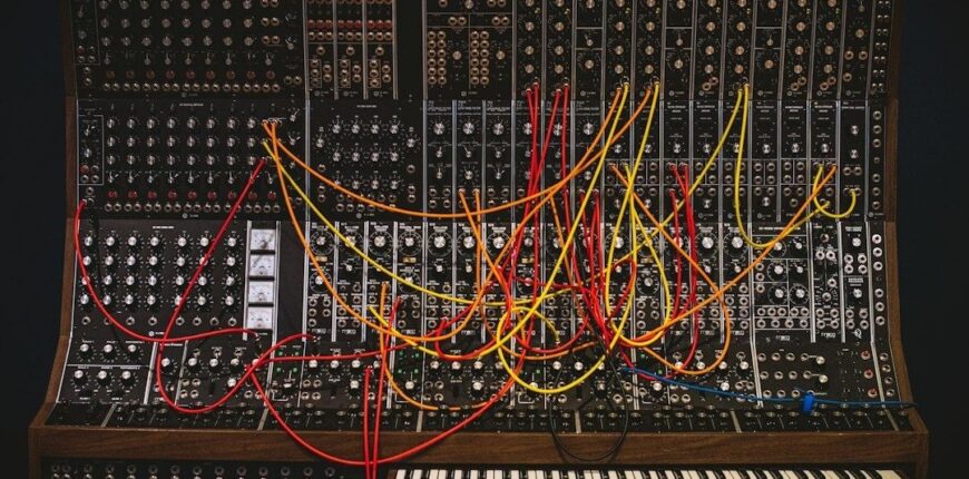 Large modular synthesizer filled with colorful patch cables and two keyboards