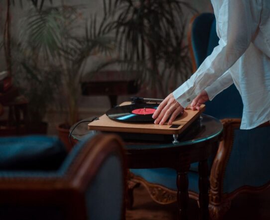 Person placing a hand near a spinning vinyl record on a turntable