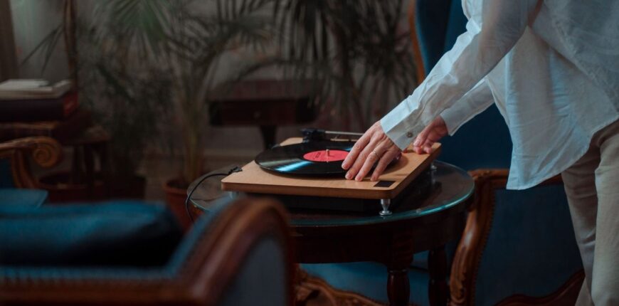 Person placing a hand near a spinning vinyl record on a turntable