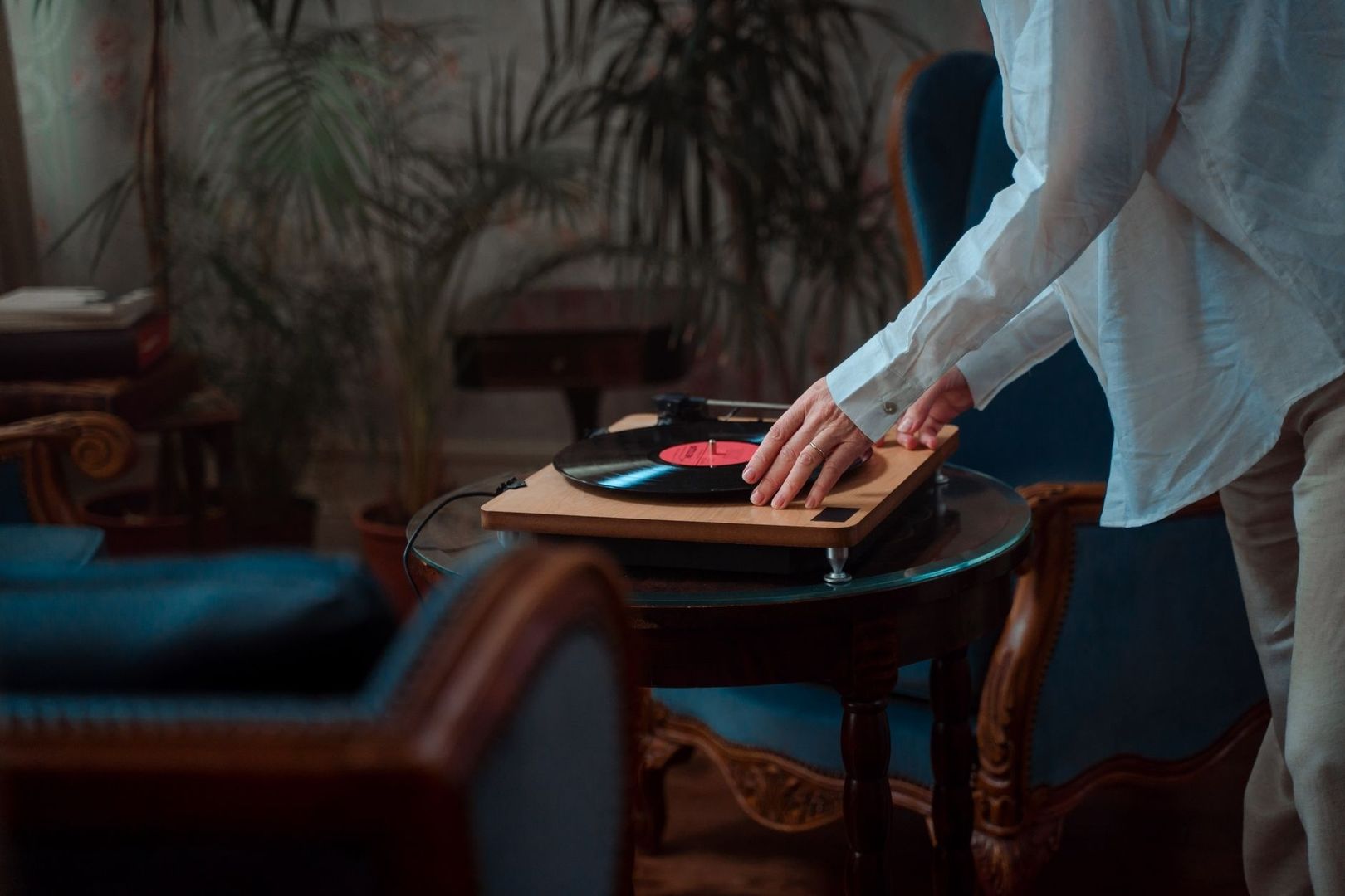 Person placing a hand near a spinning vinyl record on a turntable