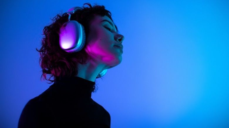 Person wearing glowing headphones and listening in colored light